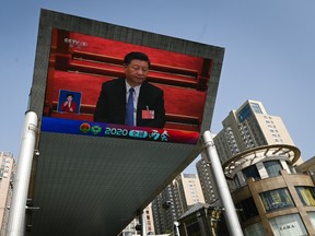 A outdoor screen shows live coverage of Chinas President Xi Jinping attending the closing session of the National Peoples Congress (NPC) in Beijing on May 28, 2020.