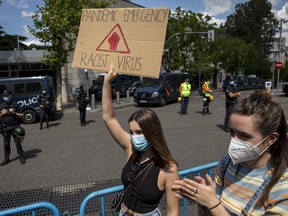 A demonstrator wears a protective mask and holds a placard during a Black Lives Matter protest following the death of George Floyd, outside the United States Embassy in Madrid on June 07.