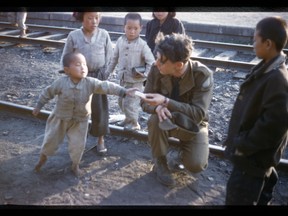 A Canadian gunner hands candy to Korean children at the rail yards in Tokchon, South Korea, in 1952.
