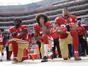 In this Oct. 2, 2016 file photo, from left, San Francisco 49ers outside linebacker Eli Harold, quarterback Colin Kaepernick and safety Eric Reid kneel during the national anthem before an NFL football game against the Dallas Cowboys in Santa Clara, Calif.