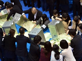Officers of the election administration committee open ballot boxes during Japan's general election, in Tokyo in 2014.