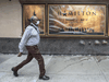 A pedestrian walks past an outdated theatre poster for Hamilton.