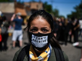 TOPSHOT - A woman poses as she wears a mask saying "I can't breathe" at the makeshift memorial in honour of George Floyd, who died while in custody of the Minneapolis police, following a day of demonstration in a call for justice on May 30, 2020 in Minneapolis, Minnesota. - Demonstrations are being held across the US after George Floyd died in police custody on May 25. (Photo by CHANDAN KHANNA / AFP) (Photo by CHANDAN KHANNA/AFP via Getty Images)