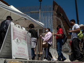 Commuters show their ID's as entering to the United States at the San Ysidro crossing port in Tijuana, Baja California state, Mexico on June 16, 2020, amid the COVID-19 coronavirus pandemic.