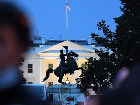 A row of police officers stand guard with the equestrian statue of former US President General Andrew Jackson behind, after protesters tried to topple it, at Lafayette square, in front of the White House, in Washington, DC on June 22, 2020.