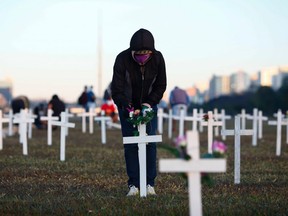 A demonstrator places flowers on a cross during a protest against Brazilian President Jair Bolsonaro and in honour of the people who died of COVID-19 in which 1000 crosses were placed in front of the National Congress in Brasilia, on June 28, 2020.