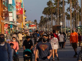 In this file photo taken on May 23, 2020 people walk at the boardwalk in Venice Beach during the first day of the Memorial Day holiday weekend in California.