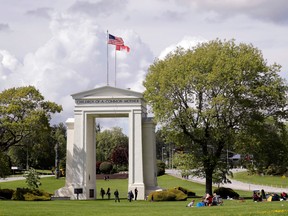 CP-Web.  In this photo taken May 17, 2020, people walk back and forth across the border between the U.S. and Canada in Peace Arch Park in Blaine, Washington.