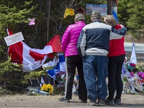 A family pays their respects to victims of the mass killings at a checkpoint on Portapique Road in Portapique, N.S. on Friday, April 24, 2020. As pressure mounts on the federal and Nova Scotia governments to call an inquiry into one of the worst mass killings in Canadian history, the country's leading scholar on inquiries says Ottawa and the province should do the right thing and work together on a joint inquest.