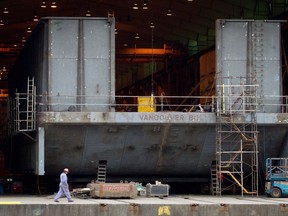 A Seaspan Vancouver Shipyards worker walks past a barge under construction in North Vancouver, B.C., on Wednesday November 2, 2011.