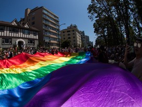 A large rainbow flag is carried by people marching in the Vancouver Pride Parade, in Vancouver, Sunday, Aug. 4, 2019.