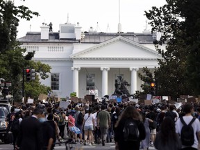 Demonstrators gather to protest the death of George Floyd, Tuesday, June 2, 2020, near the White House in Washington. Floyd died after being restrained by Minneapolis police officers. Moving among the pulsing mass of angry activism outside the White House, a handful of people are on hand to provide help and first aid to both police and protesters alike.