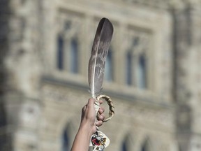 An eagle feather is held up during a rally for Missing and Murdered Indigenous Women and Girls on Parliament Hill in Ottawa on October 4, 2016. A national advocacy organization that fights for Indigenous women, girls and gender diverse people is giving the federal government a failing grade for not delivering national action plan to respond to the National Inquiry into Missing and Murdered Indigenous Women and Girls.