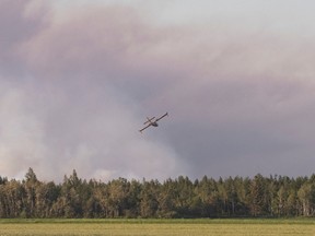 A water bomber flies toward a major field and forest fire at Lambert Peat moss fields in Riviere-Ouelle, Que., Friday, June 19, 2020. The fire spread over more than 10 kilometres, pushed by strong winds.