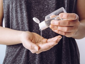 Close up view of woman person using small portable antibacterial hand sanitizer on hands.