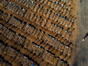 Aerial view showing a man walking past graves in the Nossa Senhora Aparecida cemetery in Manaus on June 21, 2020. - The novel coronavirus has killed at least 464,423 people worldwide since the outbreak began in China last December, being Brazil Latin America's worsthit country with 49,976 deaths from 1,067,579 cases.