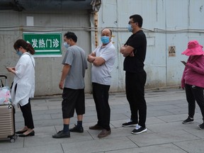 People wearing face masks line up to enter a site for nucleic acid tests at a hospital in Beijing, China, June 29, 2020.
