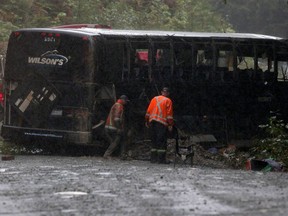 Search and rescue crews and RCMP help a tow-truck crew to remove a bus from the ditch of a logging road near Bamfield, B.C., on Saturday, September 14, 2019. A report into a bus crash that killed two University of Victoria students calls for travel during daylight hours on a narrow logging road that it says should be improved by the provincial government.