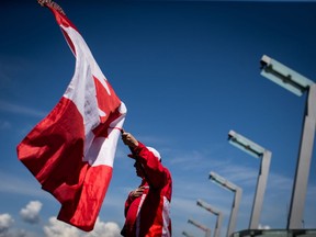 Ricky Johnson waves a Canadian flag on a hockey stick as he sings O Canada while attending Canada Day celebrations in Vancouver, on Monday July 1, 2019.