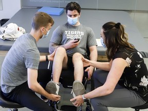 Humboldt Broncos bus crash survivor Ryan Straschnitzki, centre, works out with the help of physiotherapists Jill Truman, right, and Matthew Wright, during a training session in Calgary on Thursday, June 25, 2020, with a new epidural stimulator he received in Thailand last fall.