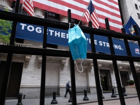 A mask hangs on a fence outside the New York Stock Exchange in May.