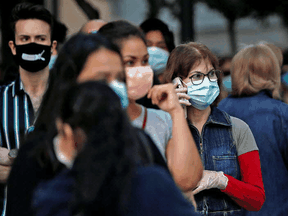 People in Madrid wear face masks before entering a re-opened store, as Spain eases its COVID-19 lockdown restrictions, June 11, 2020.