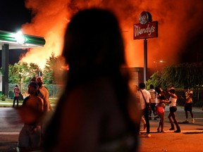 People watch as a Wendy’s burns following a rally against racial inequality and the police shooting death of Rayshard Brooks, in Atlanta, Georgia, U.S. June 13, 2020.