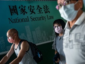 Pedestrians walk past a government-sponsored advertisement promoting a new national security law imposed by Beijing, in Hong Kong on June 30, 2020.