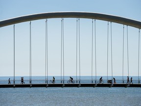 People get exercise in the warm weather as they cross the Humber Bay bridge over looking Lake Ontario during the COVID-19 pandemic in Toronto on Tuesday, June 9, 2020.
