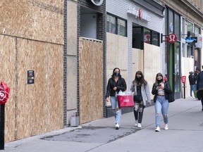 Shoppers walk past boarded up stores on Montreal's Sainte-Catherine street on Wednesday, June 3, 2020. A number of shops remain closed after being allowed to reopen last week.