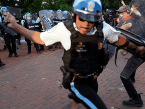 An officer swings a baton as police clash with people protesting the death of George Floyd, near the White House in Washington.