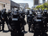 Police officers in riot gear face-off with demonstrators in downtown San Diego following the death of George Floyd.