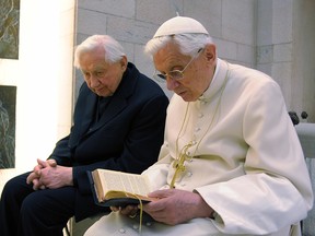 In a file photo from the Vatican press office, Pope Benedict XVI, right, prays with his brother, Msgr. Georg Ratzinger, on April 14, 2012. Former pope Benedict travelled from the Vatican to Germany on June 18, 2020, to visit his ailing brother, a rare foreign outing that came after coronavirus lockdowns were relaxed.