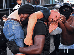 Protester Patrick Hutchinson carries an injured counter-protester to safety, near the Waterloo station during a Black Lives Matter protest in London, England, June 13, 2020.
