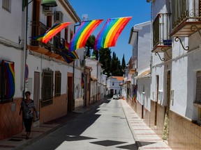 A woman walks past rainbow flags placed on a street during the International LGBT Pride Day, in Villanueva de Algaidas, southern Spain June 28, 2020.