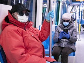 A couple wearing a protective masks ride a near-empty subway train in Montreal, on Wednesday, April 22, 2020.