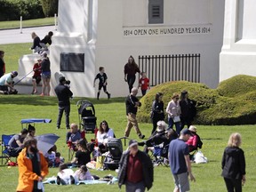 In this photo taken May 17, 2020, people picnic, play and walk back and forth across the border between the U.S. and Canada in Peace Arch Park in Blaine, Wash. British Columbia park that straddles the 49th parallel with Washington state will be closed because it's overwhelmed with visitors using it as a cross-border meeting point. THE CANADIAN PRESS/AP Photo/Elaine Thompson)