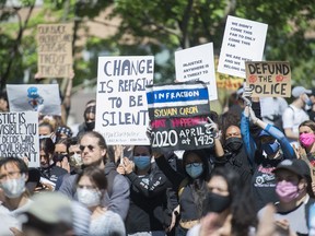 People hold up signs during a demonstration calling for justice for the death of George Floyd and other victims of police brutality, in Montreal, on June 7, 2020. A new poll suggests more Canadians are questioning their trust in the police as protests against racism and police brutality sweep across the world.