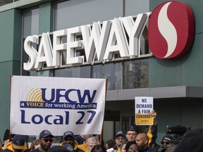 Activists hold signs during a United Food and Commercial Workers rally at the Safeway store, Wednesday, Feb. 19, 2020, in Washington. The union representing Canada Safeway workers in Alberta says it is consulting with its members about a possible strike vote.