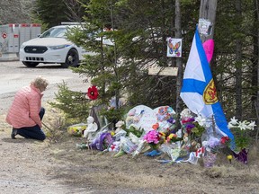 A woman pays her respects to victims of a mass shooting at a roadblock in Portapique, N.S. on Wednesday, April 22, 2020. More than seven weeks after a man disguised as a Mountie killed 22 people in rural Nova Scotia, the RCMP have finally hinted at what may have motivated one of the worst mass killings in Canadian history.