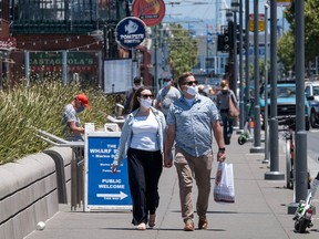 People wearing protective masks walk on Jefferson Street on Fisherman's Wharf in San Francisco, California, U.S., on Monday, June 22, 2020.