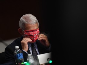 Anthony Fauci, director of the National Institute of Allergy and Infectious Diseases, adjusts a Washington Nationals protective mask during a Senate committee hearing in Washington, D.C., U.S., on Tuesday, June 30, 2020.
