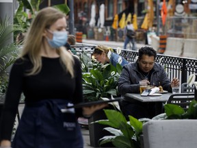 People sit on an outdoor patio in Toronto, on Wednesday, June 24, 2020.