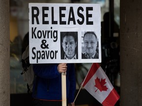 A man holds photographs of Michael Kovrig and Michael Spavor, who have been detained in China for two years, outside the B.C. Supreme Court in Vancouver in a file photo from Jan. 21, 2020.