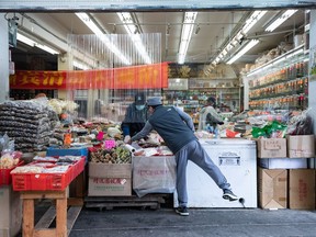 A man assists a customer from behind a plastic divider at a store in Chinatown, in Vancouver, B.C., Wednesday, June 10, 2020.