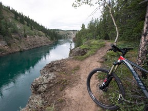 A mountain biker rides a trail that follows the Yukon River near Whitehorse on Friday, July, 22, 2016.