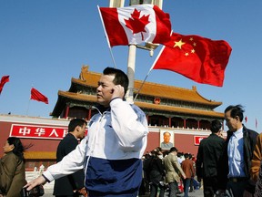 A man walks past Canadian and Chinese flags in front of Tiananmen Gate in Beijing, ahead of a four-day official visit by Prime Minister Jean Chretien in 2003.