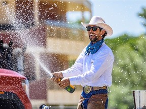 The 2020 Calgary Stampede Marshal Filipe Masetti Leite sprays a champagne on the stage at the Calgary Stampede Grandstand on Friday, July 3, 2020. He has arrived in Calgary after an eight year journey of crossing the Americas on horseback.