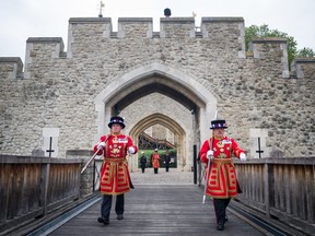 Yeoman Warders, commonly known as Beefeaters, march across the Middle Drawbridge during a ceremonial event to mark the reopening to the public of the Tower of London on July 10, 2020 in London, England.