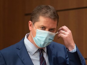 Leader of the Opposition Andrew Scheer removes a face mask as he makes his way to the podium for a news conference, Wednesday, July 8, 2020 in Ottawa.
